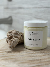 Jar of 'Cake Batter' whipped soap with a natural sponge on a wooden surface.