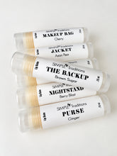 Five lip balm tubes arranged diagonally on a white background, featuring labels for Simple Traditions lip balms including Cherry, Asian Pear, Brown Sugar, Berry Blast, and Ginger.