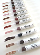 Set of lip gloss tubes with swatches on a white background
